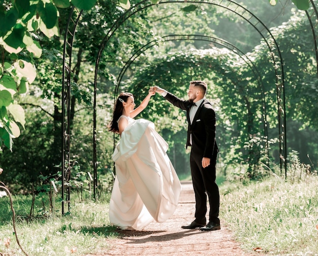 sposa e sposo che ballano sotto l'arco di nozze