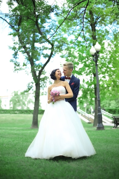 Sposa e sposo che camminano nel parco. all'aperto