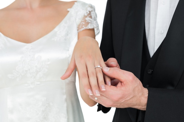 Sposa e sposo che mostrano fede nuziale contro fondo bianco