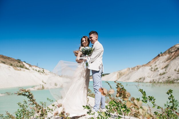 Sposa e sposo che posano in natura con un mazzo di nozze