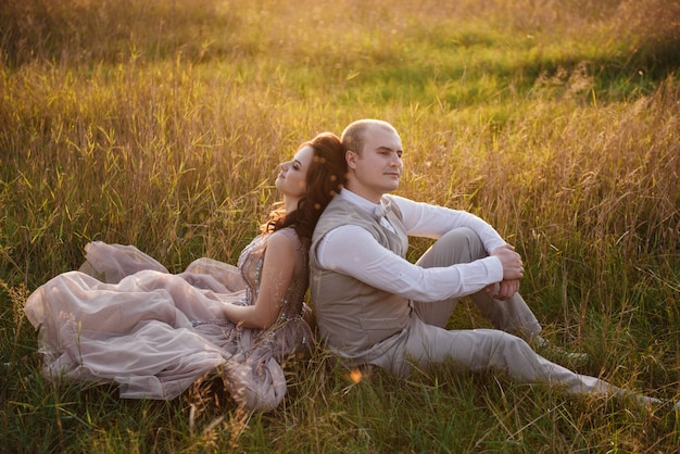 Sposa e sposo che posano nel campo al tramonto