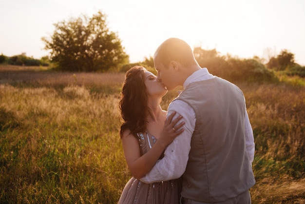 Sposa e sposo che posano nel campo al tramonto