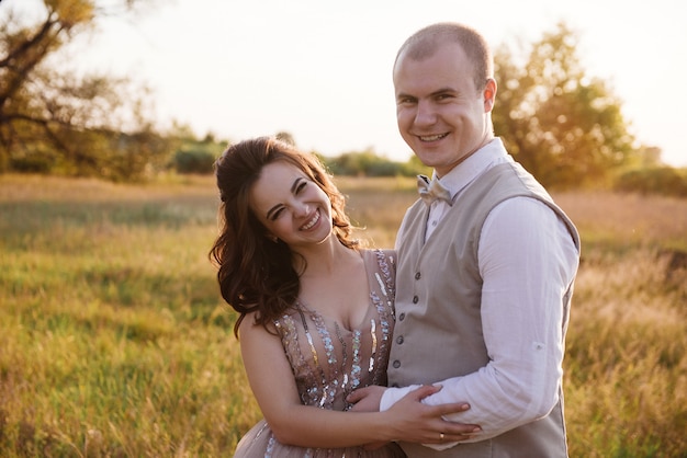 Sposa e sposo che posano nel campo al tramonto