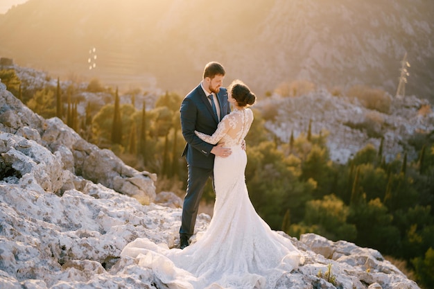 Sposa e sposo che si abbracciano sulla montagna rocciosa