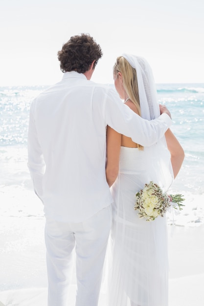 Sposa e sposo che si affacciano sul mare che abbraccia