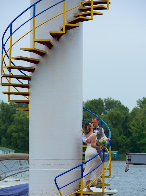 Sposa e sposo che si baciano vicino al faro