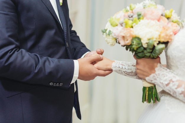 Sposa e sposo che si tengono per mano alla cerimonia di nozze