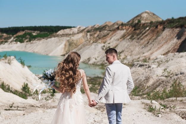 Sposa e sposo che si tengono per mano in natura