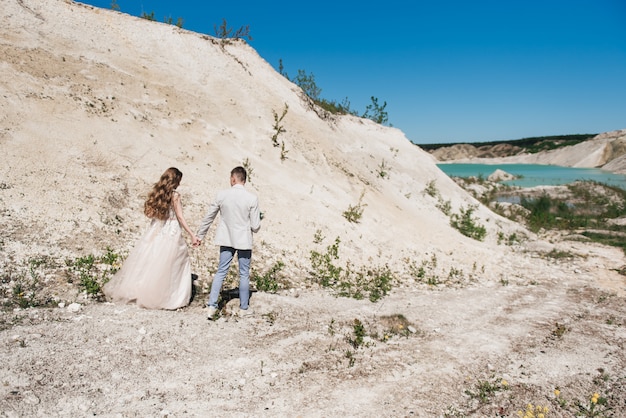 Sposa e sposo che si tengono per mano in natura