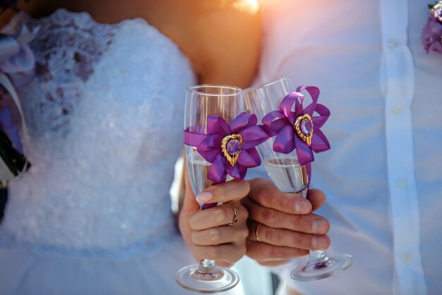 Sposa e sposo che tengono i vetri di champagne in loro mani, primo piano.