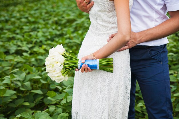 Sposa e sposo che tengono il bello mazzo di nozze