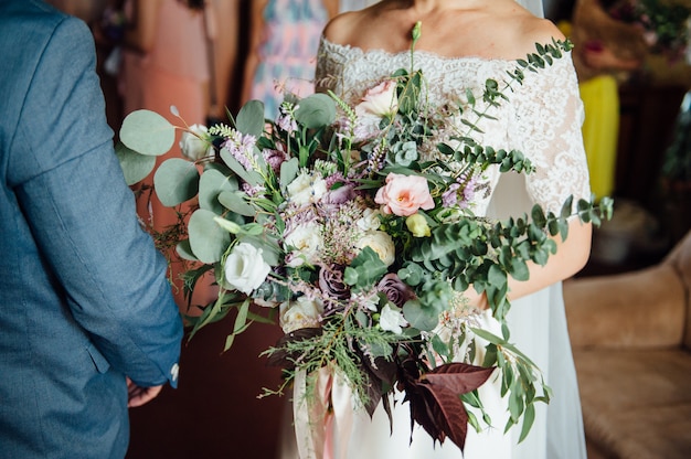 Sposa e sposo che tengono insieme il mazzo di nozze