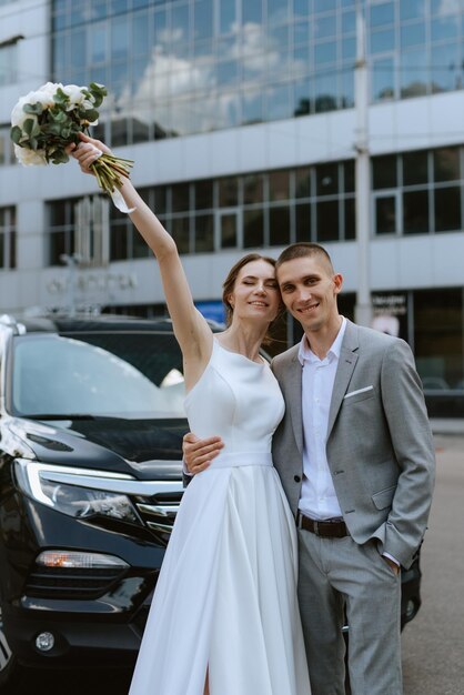 sposa e sposo con un'auto nera