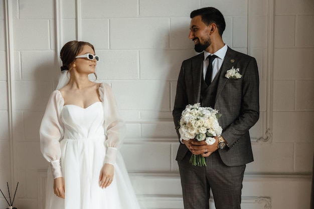 Sposa e sposo davanti a un muro bianco