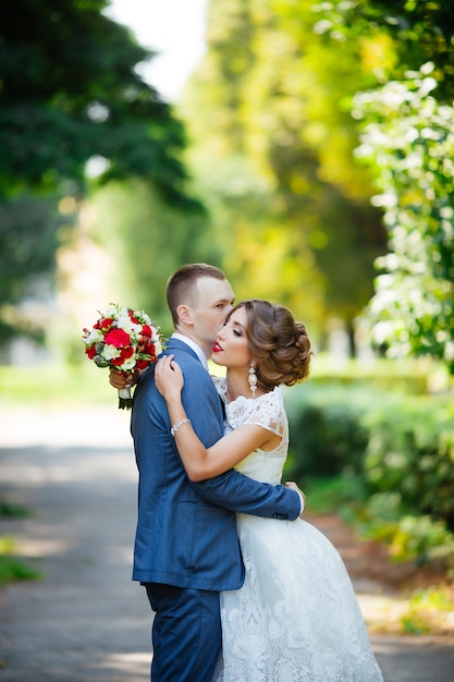 Sposa e sposo eleganti che propongono insieme all'aperto su un giorno delle nozze