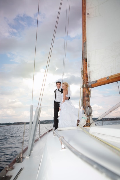 Sposa e sposo felici che abbracciano su uno yacht