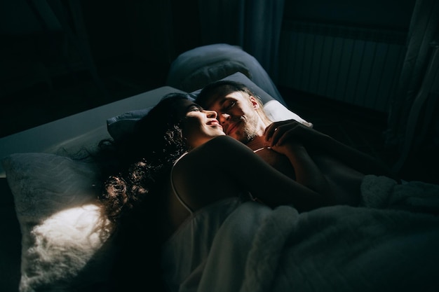 Sposa e sposo felici che si abbracciano e si baciano a letto Mattina di nozzex9xA