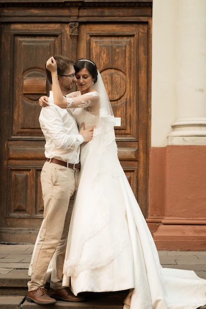 Sposa e sposo felici romantici di lusso che celebrano il matrimonio sullo sfondo della vecchia città soleggiata