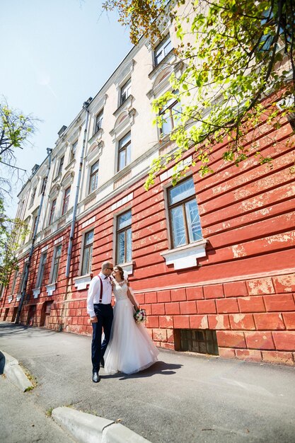 Sposa e sposo in abiti da sposa che camminano lungo le strade della città il giorno del matrimonio