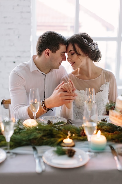 Sposa e sposo in posa al tavolo del banchetto decorato nel corridoio bianco