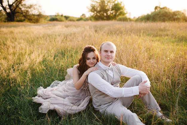 Sposa e sposo in posa attraverso il campo al tramonto