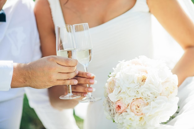 Sposa e sposo in possesso di bouquet da sposa e bicchiere di champagne