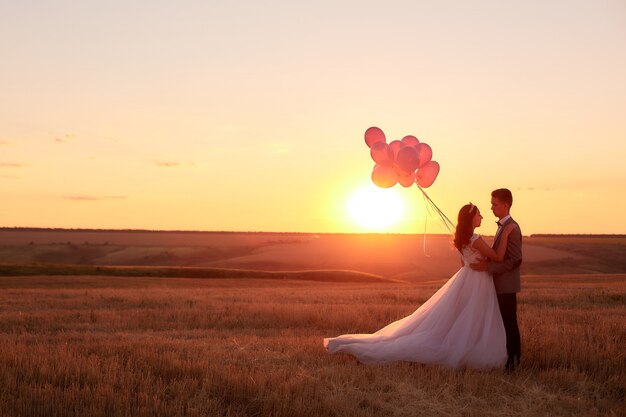 Sposa e sposo in un campo al tramonto con l'aerostato.