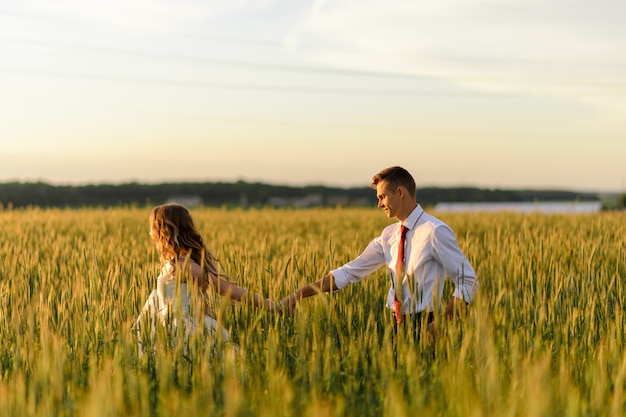 Sposa e sposo in un campo di grano. Una donna conduce un uomo per mano.