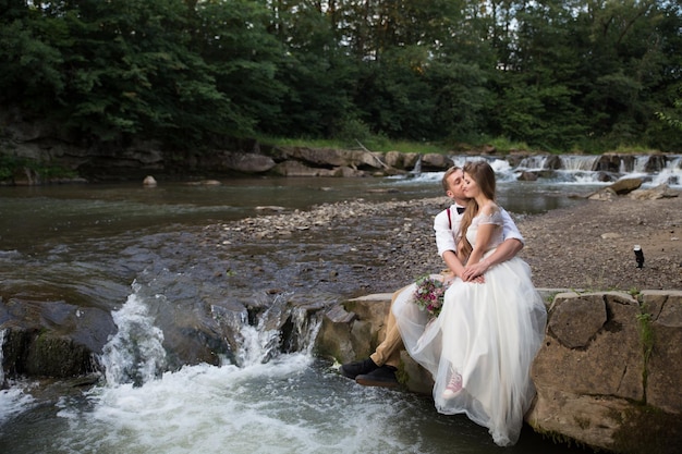 Sposa e sposo vicino al fiume di montagna