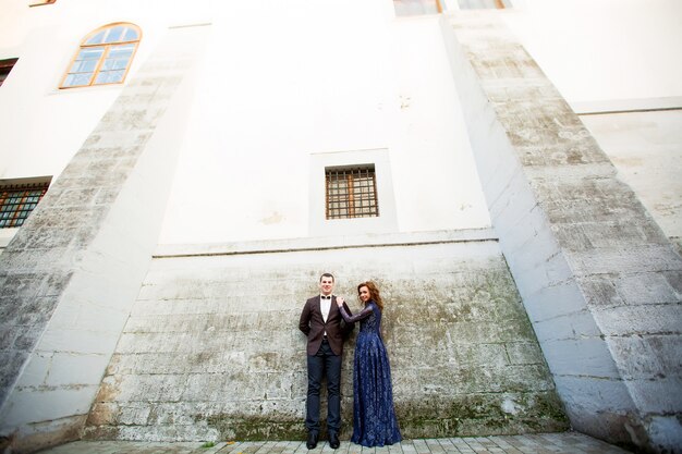 Sposa felice che sta al sorridere grigio della parete