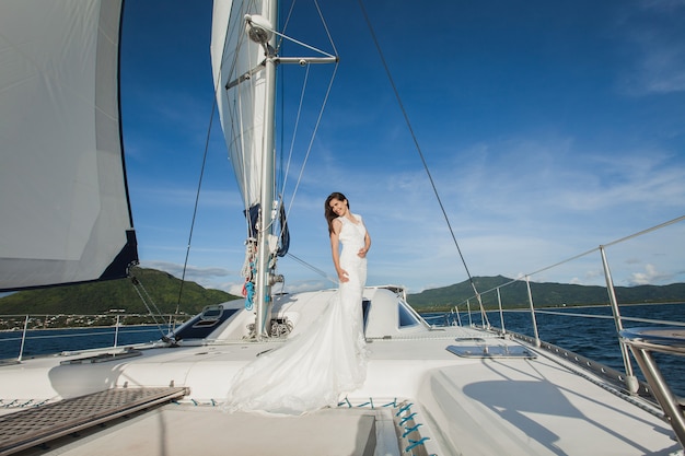 Sposa felice su uno yacht. Lo yacht bianco con il set di vele percorre l'isola