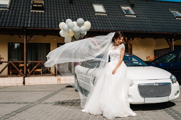 Sposa felice vicino a casa fuori città e convertibile