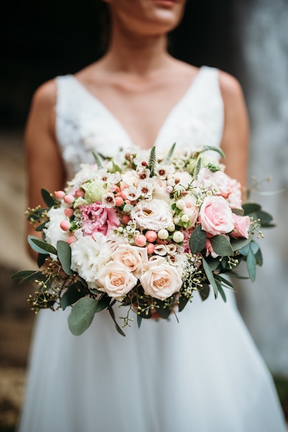 Sposa in abito bianco con bouquet da sposa con fiori rosa