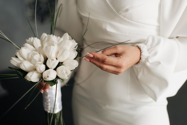 Sposa in abito bianco con bouquet da sposa nelle mani dettagli del matrimonio