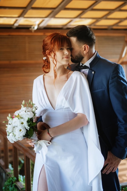 Sposa in abito bianco con bouquet e sposo in abito blu
