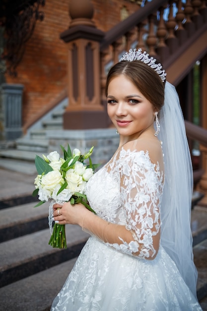 Sposa in abito bianco con un bouquet in mano e una corona in testa