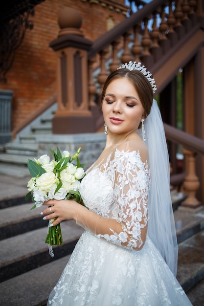 Sposa in abito bianco con un bouquet in mano e una corona in testa