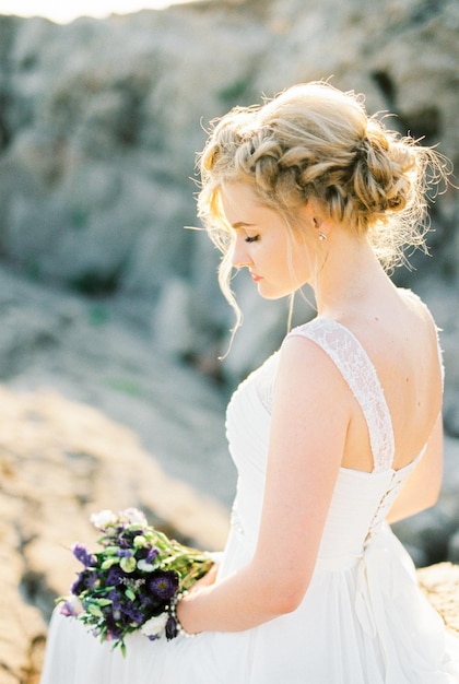 Sposa in abito bianco con un mazzo di fiori Vista laterale