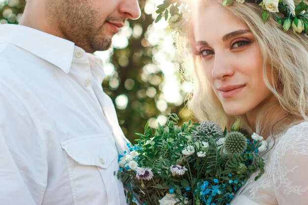 Sposa in abito bianco e corona e ritratto dello sposo in una giornata estiva Concetto di matrimonio all'aperto rustico