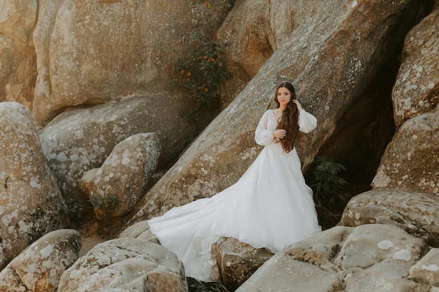 Sposa in abito bianco in piedi sulla collina e guardando il tramonto.