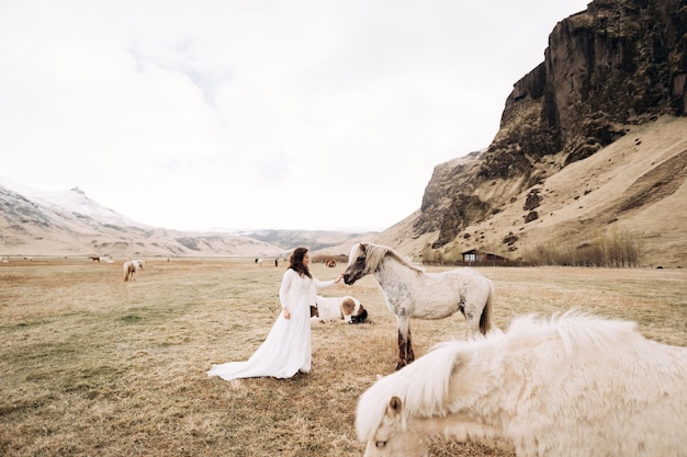 Sposa in abito bianco in un campo con cavalli destinazione sessione fotografica di nozze islanda