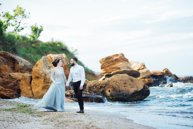 sposa in abito blu cammina lungo la riva dell'oceano