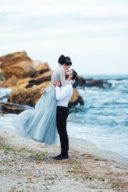 sposa in abito blu cammina lungo la riva dell'oceano