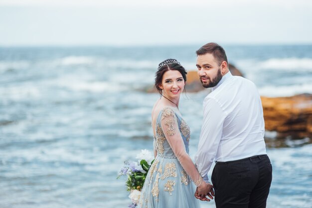 sposa in abito blu cammina lungo la riva dell'oceano