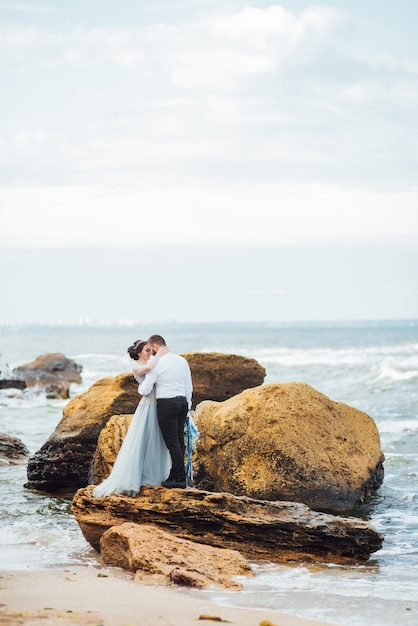 sposa in abito blu cammina lungo la riva dell'oceano