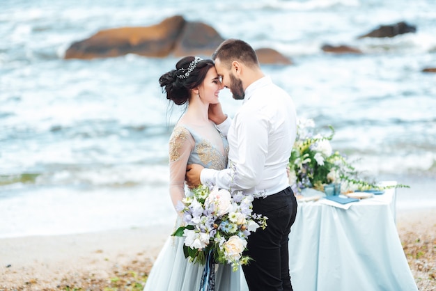 sposa in abito blu cammina lungo la riva dell'oceano