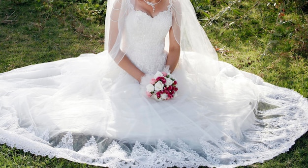 Sposa in abito da sposa bianco con ricamo in pizzo Un mazzo di fiori nelle mani della sposa