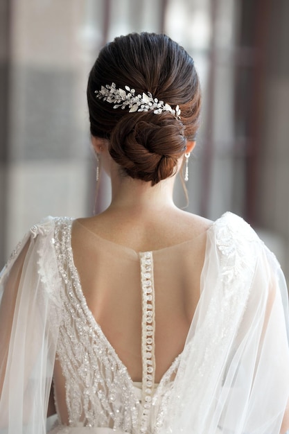 Sposa in abito da sposa da dietro con acconciatura glam bun all'aperto