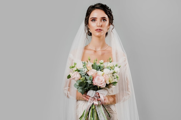 Sposa in abito da sposa e sorrisi di bouquet di velo. Ragazza in abito da sposa.