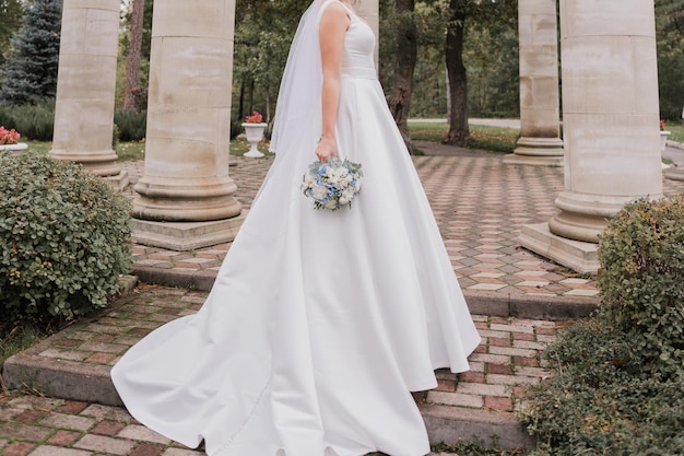 Sposa in abito da sposa in colonne nel parco